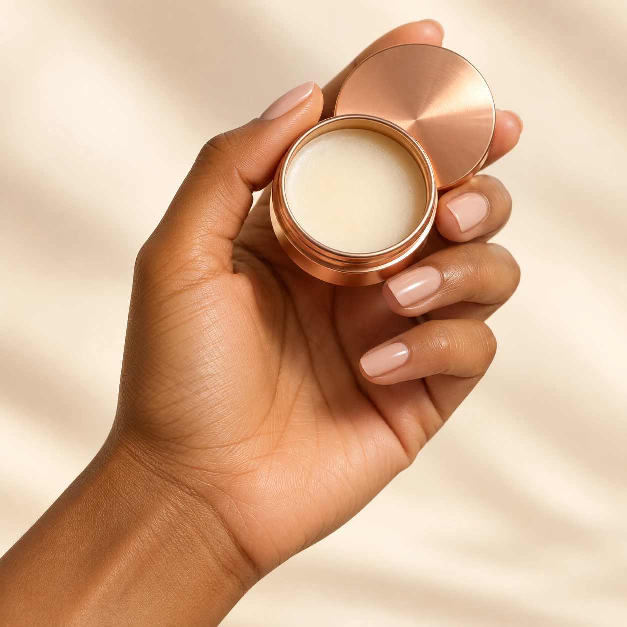 Hand holding an open rose-gold solid perfume packaging concept